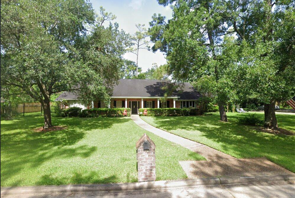 Large traditional home framed by mature oak trees
